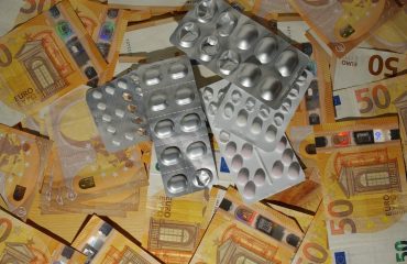 A pile of silver dices sitting on top of a pile of money